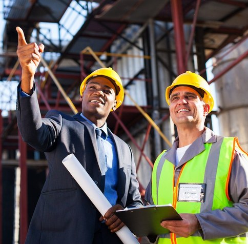 Two contractors in hard hats reviewing plans on site
